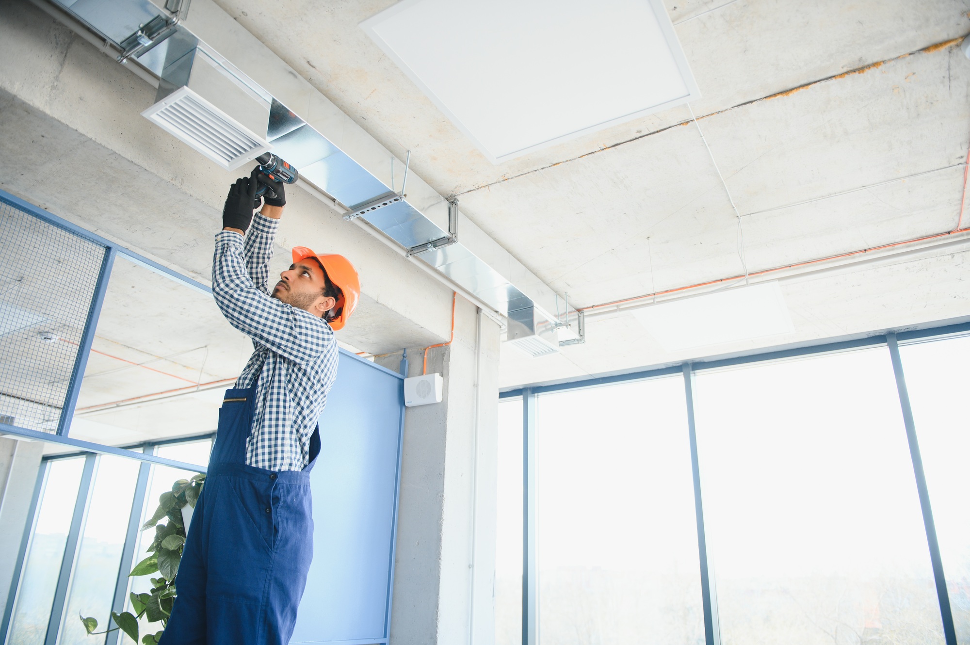 hvac services - indian worker install ducted pipe system for ventilation and air conditioning